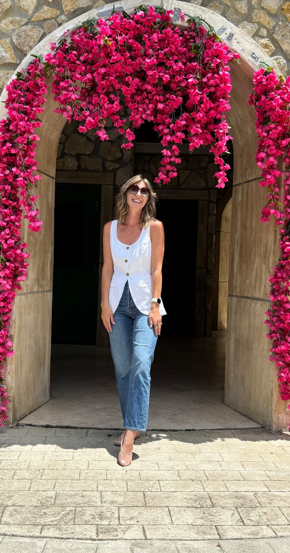 Kasey Ryan standing beneath a bright pink bougainvillea flower arch